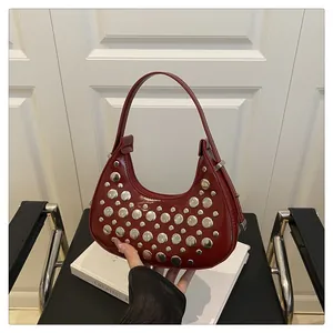 Detail of dark red glossy crescent hobo bag with stylish silver metal studs