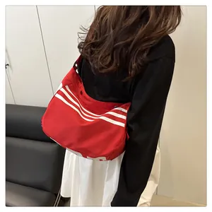 Gros plan du sac à bandoulière rouge en nylon avec rayures blanches et style sport