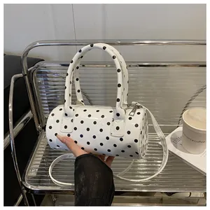 Detailed view of polka dot cylindrical handbag with glossy PU leather and top zipper
