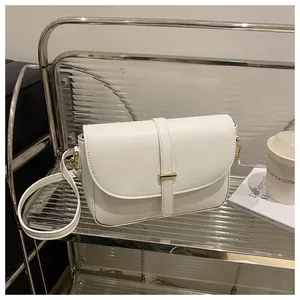 Close-up of white veg-tanned leather handbag with golden metal buckle on modern acrylic stand