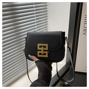 Nahaufnahme einer schwarzen matten Umhängetasche mit goldener geometrischer Metallschnalle