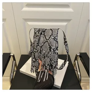 Close-up of snakeskin pattern texture and elegant long tassels on the shoulder bag