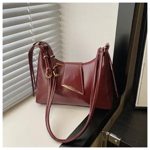Detail of burgundy PU leather saddle bag with glossy finish and gold hardware on window