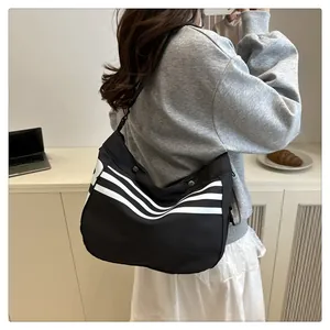 Détail d'un sac bandoulière de sport noir avec rayures blanches et sangle réglable