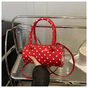 Close-up of a mini red polka dot barrel bag with glossy patent leather finish
