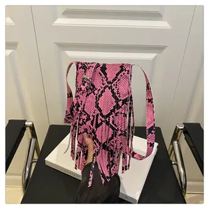 Detailed view of pink and black snake print handbag with dense leather fringe and silver buckle