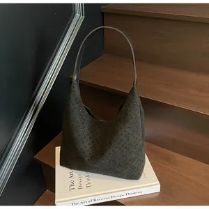Detailed view of a black suede hobo bag with mini rivets on white prop book display