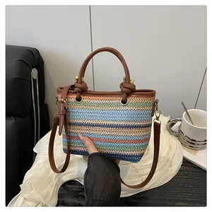 Detail of colorful woven straw bag with premium leather handles and knot accents