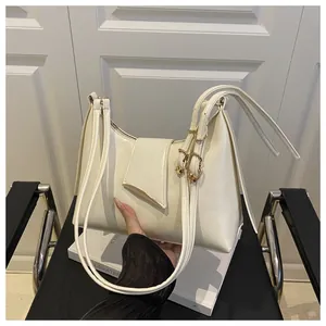 Close-up of cream PU leather underarm bag with gold hardware and half-moon silhouette
