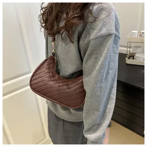 Dettaglio della borsa a mezzaluna in pelle intrecciata marrone scuro con zip dorata