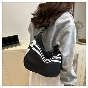 Détail du sac bandoulière croissant en nylon noir avec des rayures blanches au bureau