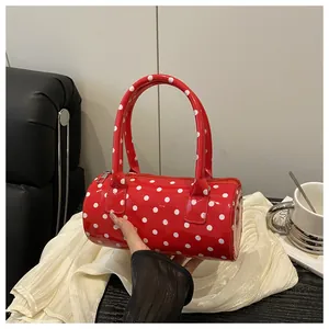 Detail of red polka dot cylinder handbag with glossy finish and zipper closure