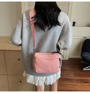 Detail of pink nylon crossbody bag featuring wide shoulder strap and functional pockets