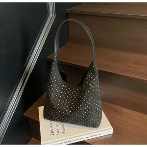Detail of black suede hobo bag featuring silver rivets on a wooden stair background