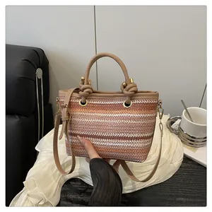 Detailed view of striped woven bag with leather knot handles and gold hardware