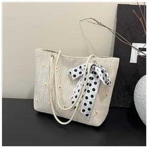 Detail of straw tote bag featuring daisy embroidery and a black polka dot silk scarf