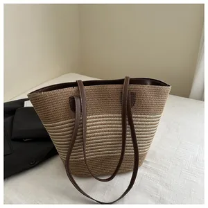 Detail of striped woven tote bag with brown leather handles and contrast stitching