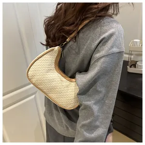 Dettaglio borsa intrecciata color panna con finiture in pelle marrone e zip in metallo