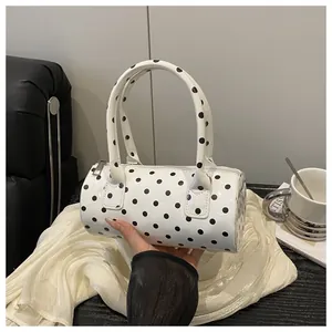 Detailed view of polka dot cylindrical handbag on minimalist fabric and sofa background