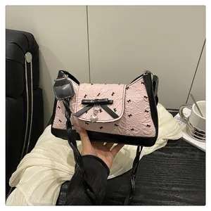 Détail du sac à bandoulière rose plissé avec nœuds noirs et pendentif en forme de cœur
