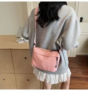 Detailed back view of pink nylon crossbody bag with adjustable strap on model