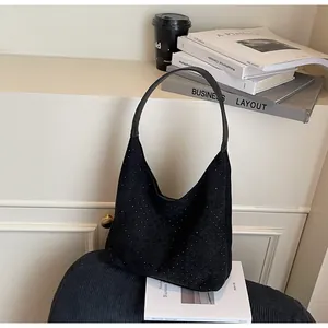 Detail of black denim hobo bag with rhinestone studs showing texture and shape