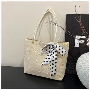 Detail of straw tote bag with daisy embroidery and polka dot ribbon on round handles