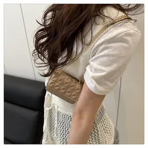 Detail of a beige quilted mini chain bag worn by a model to show stylish proportions