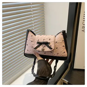 Détail du sac rose à motif nœud avec poignée nouée noire et pendentif cœur argenté