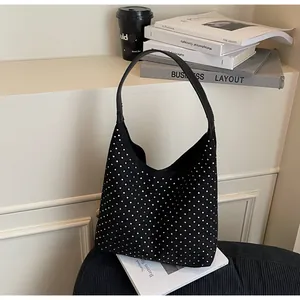 Detail of black denim hobo bag with silver rhinestone embellishments on a book background