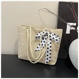 Detail of beige straw tote with daisy embroidery and a black polka dot bow ribbon