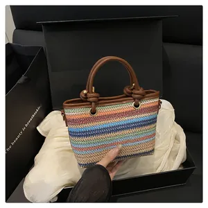 Detail of colorful woven straw tote with leather handle and decorative knot on silk fabric