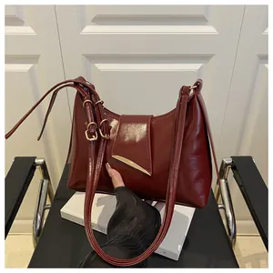 Close-up of the wine red saddle bag showing glossy leather and golden metal buckle
