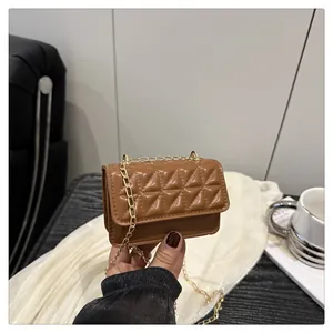 Macro view of mini quilted crossbody bag in caramel brown with gold chain strap