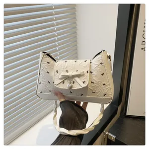 Détail du sac à bandoulière plissé blanc avec imprimés nœuds noirs et pendentif cœur