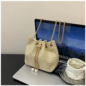 Detail of woven straw bucket bag with gold chain strap and pearl drawstring charms