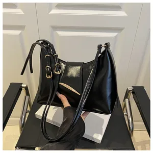 Close-up of black glossy PU leather shoulder bag with silver triangle buckle detail