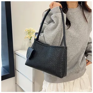 Detail of minimalist black woven leather shoulder bag with detachable mini pouch