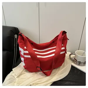 Détail d'un sac cabas rouge au design à trois bandes avec une large bandoulière réglable