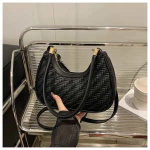 Dettaglio borsa a mezzaluna in pelle nera intrecciata con cerniera e finiture dorate