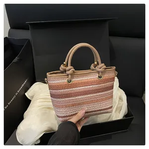 Detail of the woven striped handbag featuring leather handles and gold metal hardware