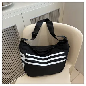 Détail du sac bandoulière noir avec quatre rayures blanches et grand logo lettre R
