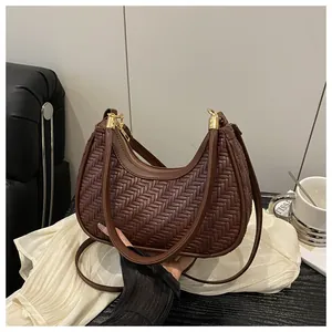 Dettaglio di una borsa a mezzaluna intrecciata marrone con cerniera dorata e texture