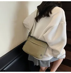 Detail view of olive green canvas crossbody bag worn by a model in a stairwell
