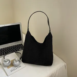 Minimalist black studded denim underarm bag with spacious tote design on a modern desk