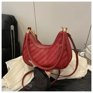 Dettaglio ravvicinato della borsa a mezzaluna rossa intrecciata con fibbie d'oro