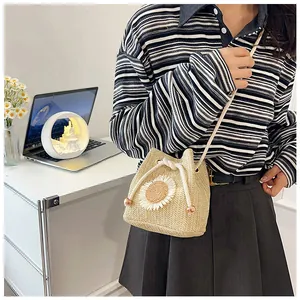 Detail of hand-woven straw bucket bag with white sunflower design and drawstring closure
