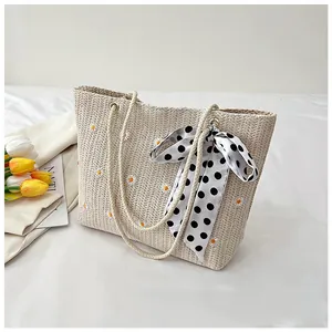 Detail of straw tote bag with daisy embroidery, cotton rope handles, and polka dot scarf