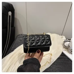 Close-up of a mini black quilted chain bag held by a model in a lifestyle setting