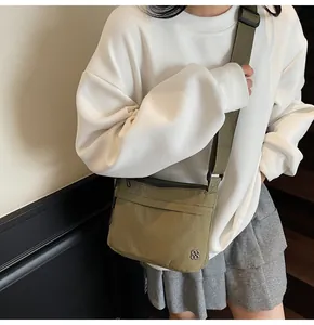 Detailed view of olive green nylon crossbody bag with adjustable strap and clover logo